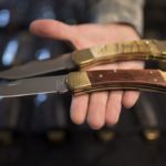 man holds two folding knives on palm