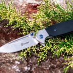 silver and black folding knife on green grass